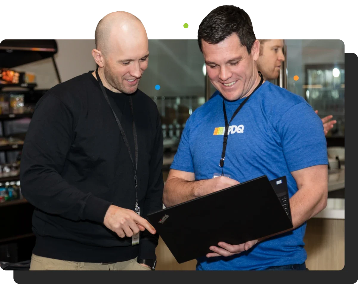 photo of 2 pdq employees looking at laptop