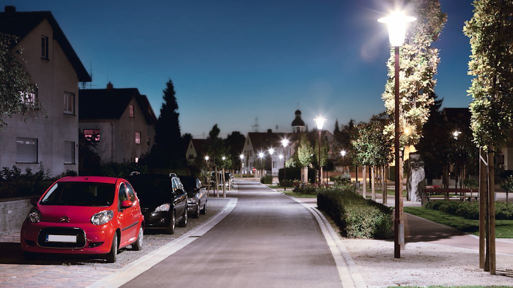 Nachtansicht einer Wohnstraße mit parkenden Autos.