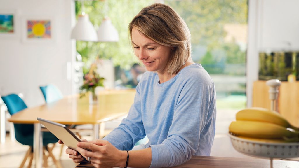 Frau benutzt Tablet in ihrer hellen Küche.