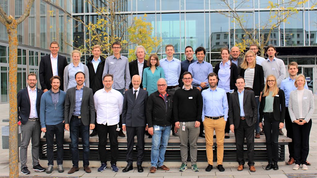 Gruppenfoto mit vielen Menschen vor einem verglasten Gebäude.