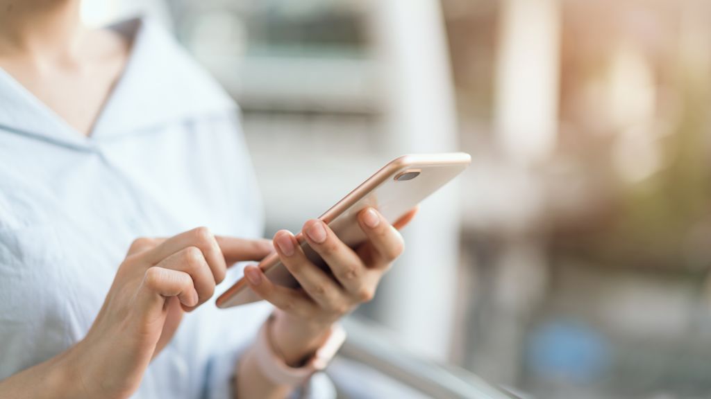 Frau hält Smartphone in der Hand und bedient es.