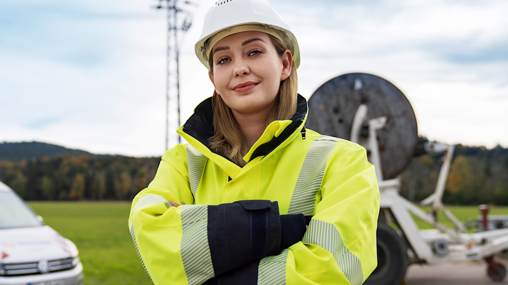 Frau in Sicherheitsjacke mit Helm schaut freundlich in die Kamera.