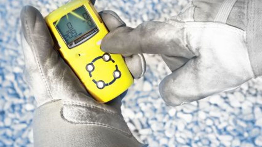 Gelber Gasdetektor in Arbeitshandschuhen.