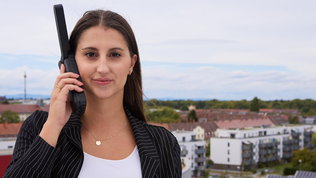 Junge Frau hält Satellitentelefon an ihr rechtes Ohr.