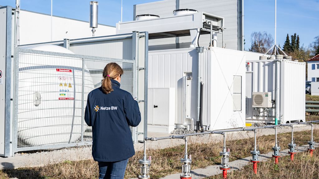 Eine Netze-BW-Mitarbeiterin steht vor technischen Anlagen des NETZlabors H₂-100 in Öhringen.