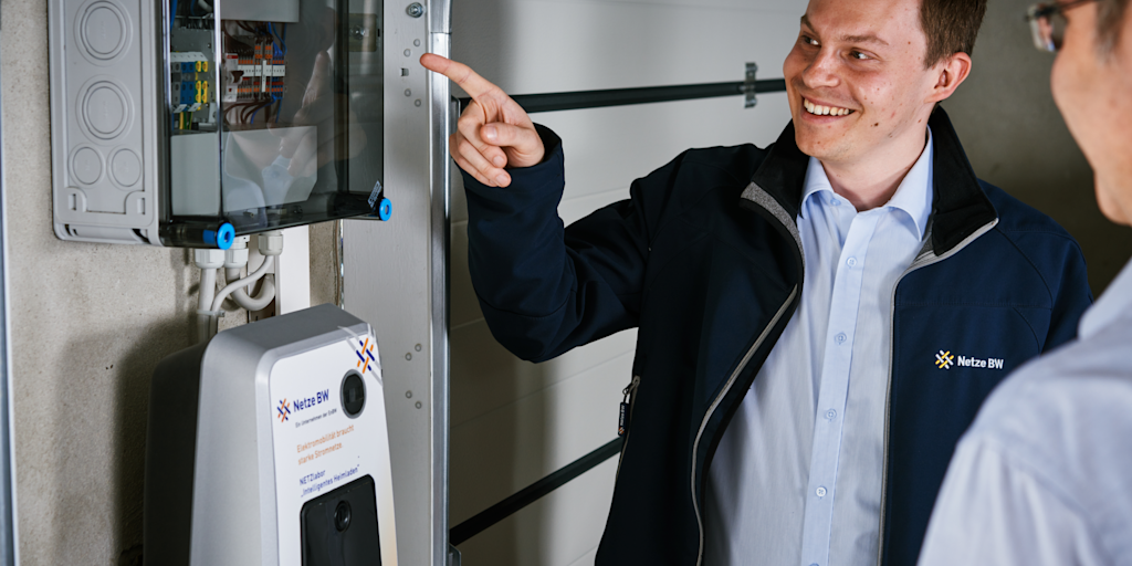Mann zeigt auf Elektroladesäule und Sicherungskasten.