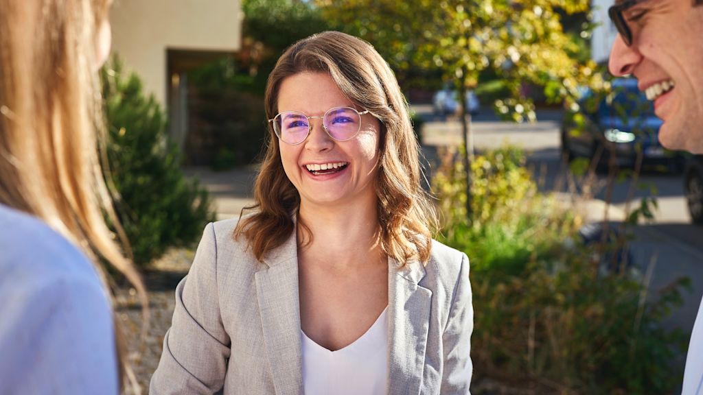 Lächelnde junge Frau mit Brille und im beigen Blazer.