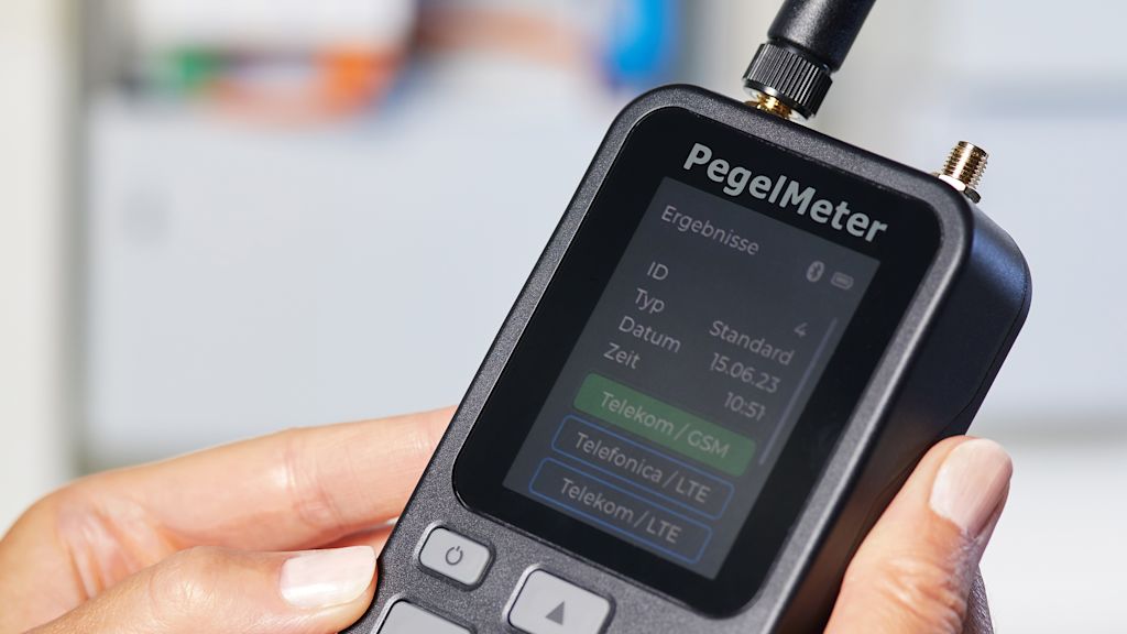 Ein PegelMeter wird von zwei Händen gehalten und es wird als Beispiel die Oberfläche des PegelMeters gezeigt.