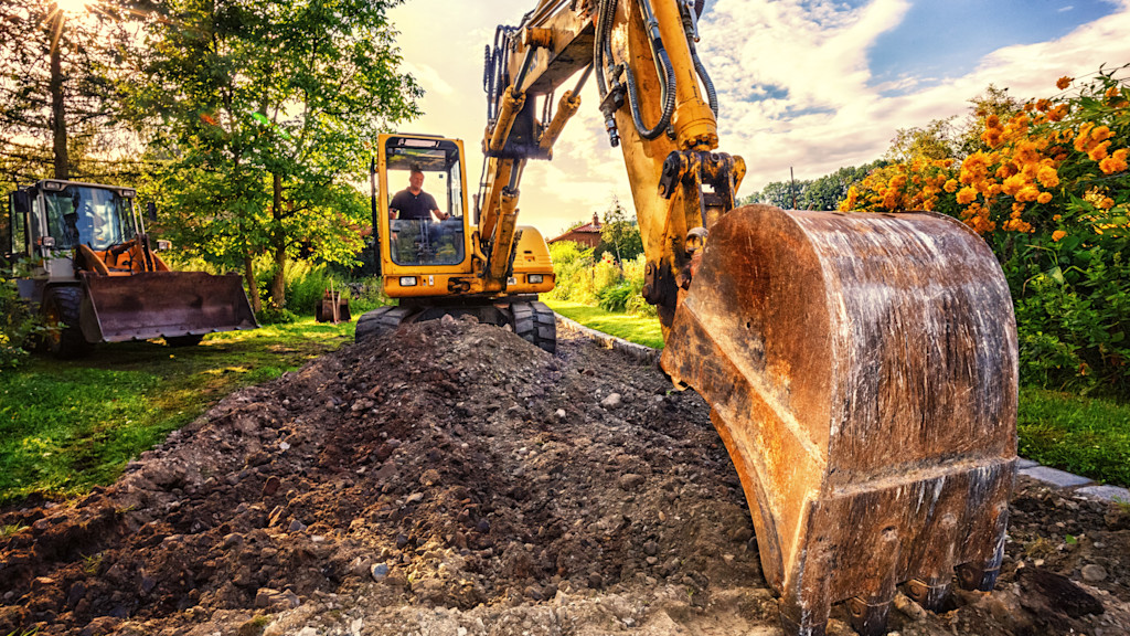 Gelber Bagger gräbt im Garten.