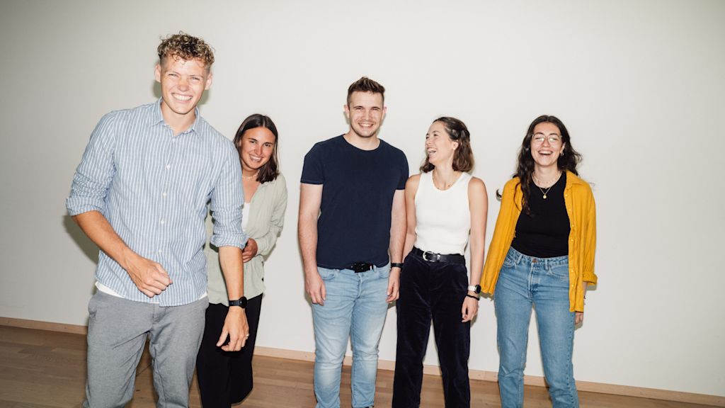 Fünf junge Menschen lächeln in die Kamera und machen ein Selfie.