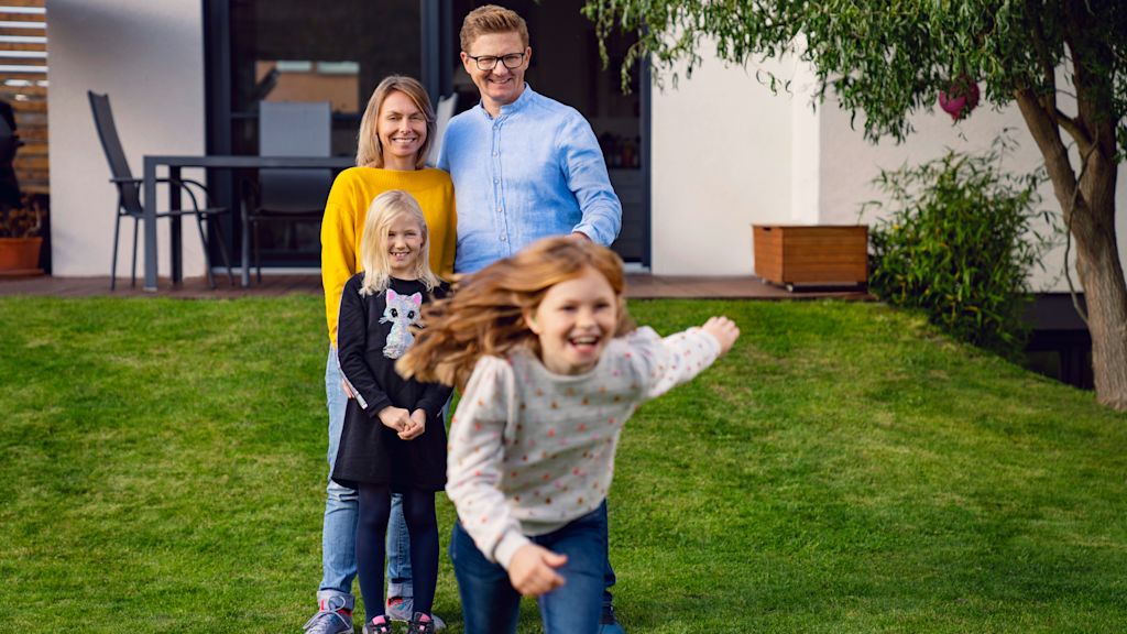Mann, Frau und zwei Mädchen im Garten, Kinder spielen.