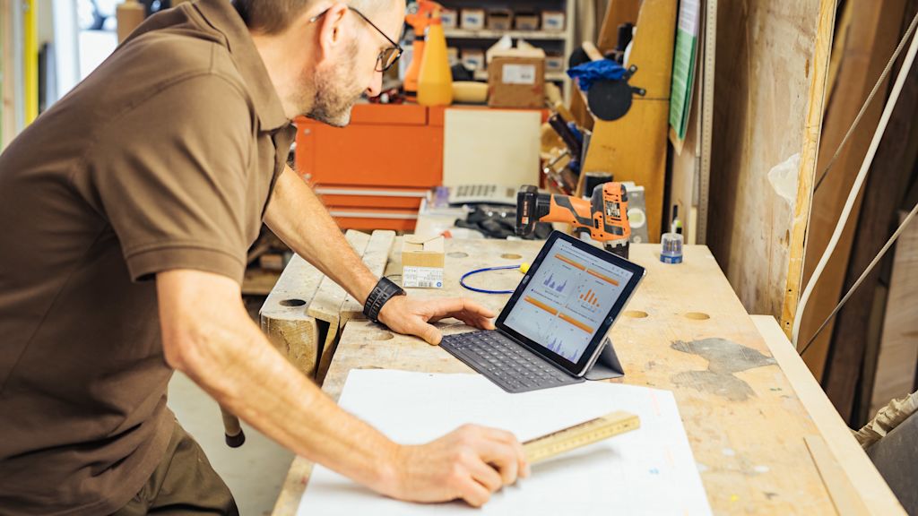 Handwerker überprüft Daten auf Tablet in Werkstatt.