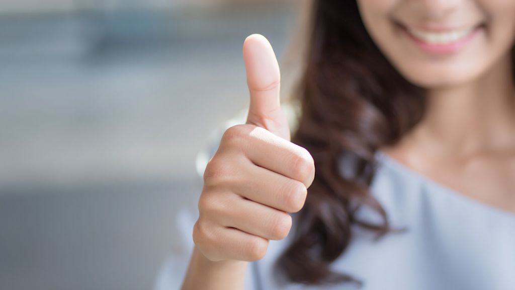 Frau hält lächelnd ihren Daumen hoch.