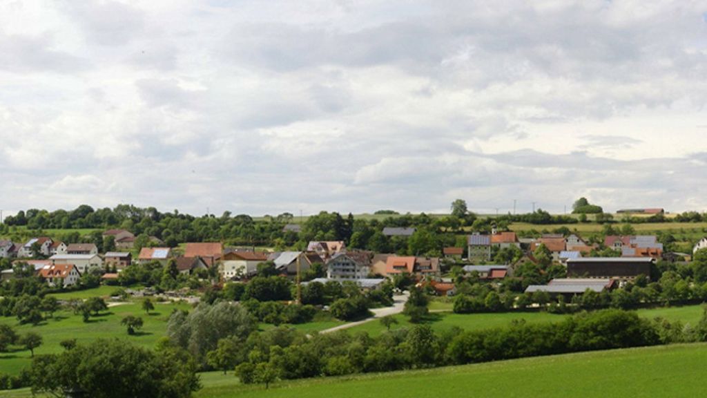 Landschaft mit einem kleinen Dorf im Hintergrund.
