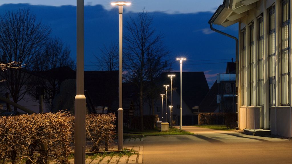 Gut beleuchteter Parkplatz am Abend mit gleichmäßig verteilten LED-Laternen. Die blendfreie Beleuchtung sorgt für Orientierung und mehr Sicherheit für alle Verkehrsteilnehmenden.