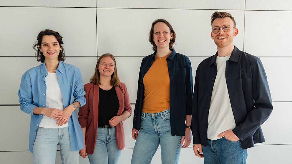 Vier Trainees der Netze BW GmbH stehen lächelnd vor einer weißen Wand.