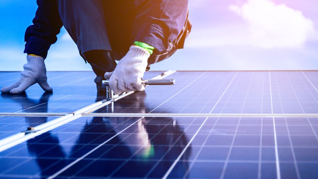 Handwerker befestigt Solarmodule auf einem Dach.