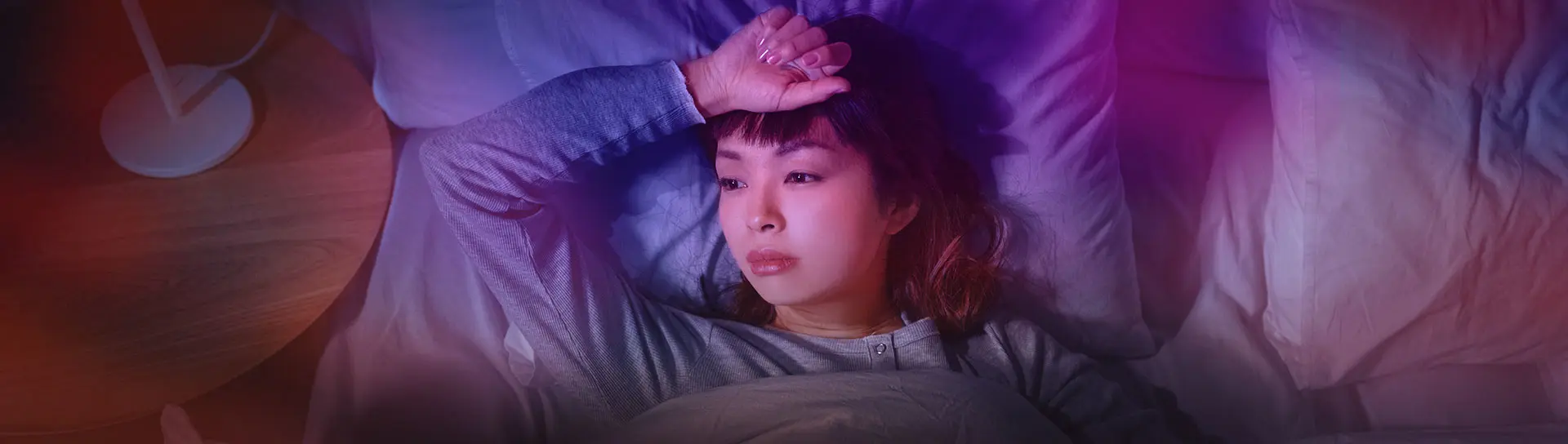 Sleepless Asian woman lying in bed at night.