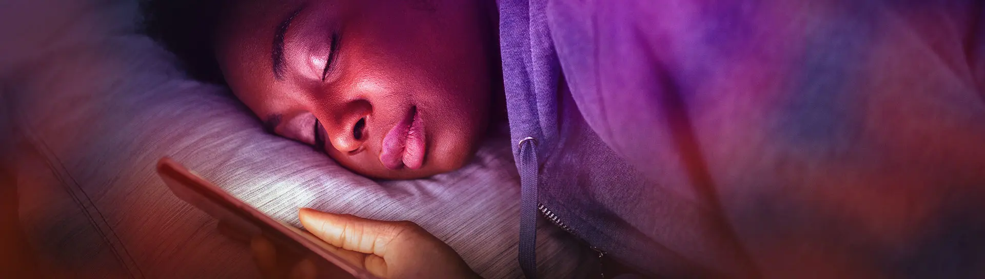 Close up portrait of African American woman holding mobile phone and sleeping.