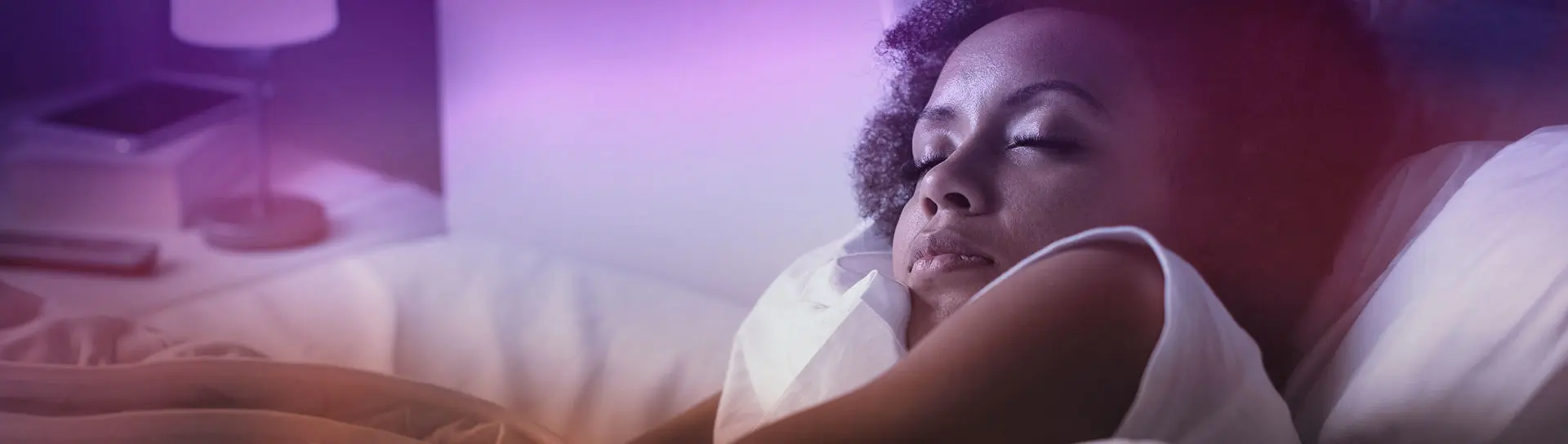 Young African woman sleeping in bed at night, soft light on.