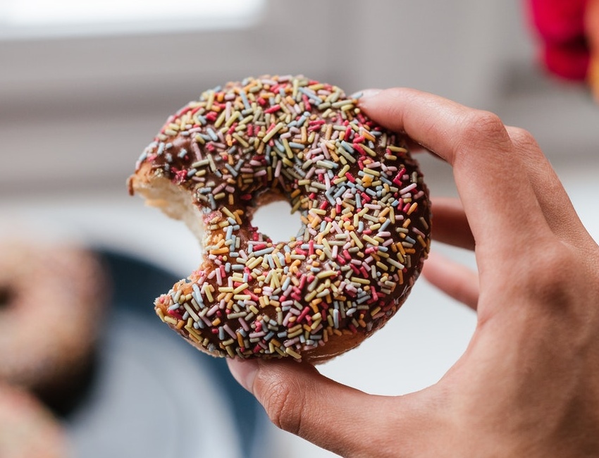 Hand holding a doughnut with coloured sprinkles