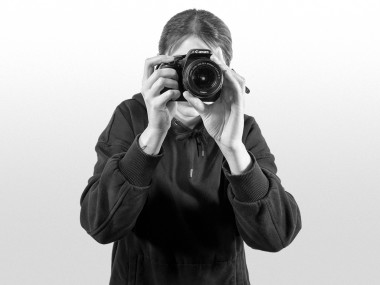 Frau mit einer Fotokamera vor dem Gesicht