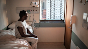 Sad patient sitting on hospital bed looking out window