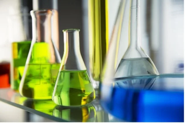 Various sized beakers with different colored liquids on table surface