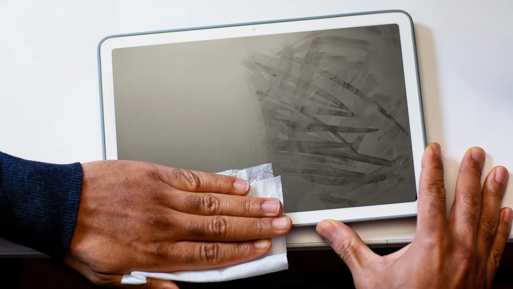 Hands wiping a tablet device with a disposable wipe