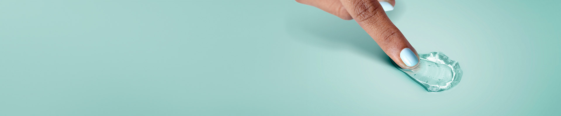 Doigt touchant une petite quantité de gel transparent sur fond vert clair, illustrant un produit de soin.