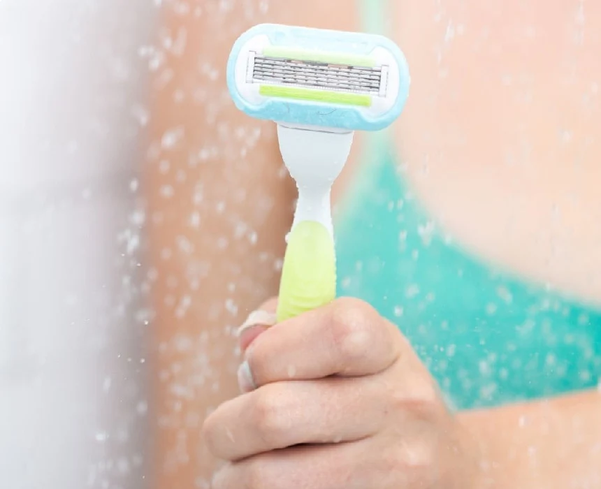 Femme tenant un rasoir sous la douche