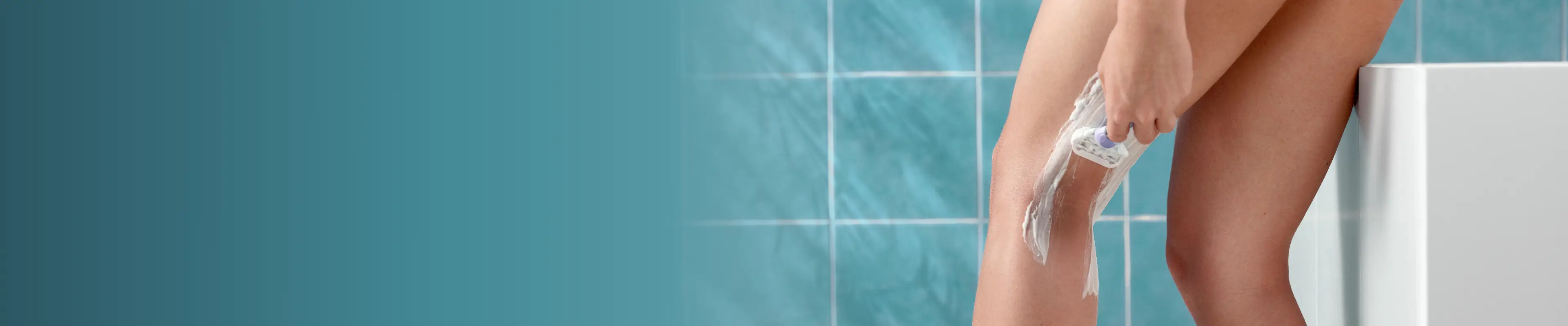 Une femme est assise dans une baignoire et se rase la jambe avec un rasoir Gillette Venus, entourée d'une salle de bains carrelée et lumineuse.