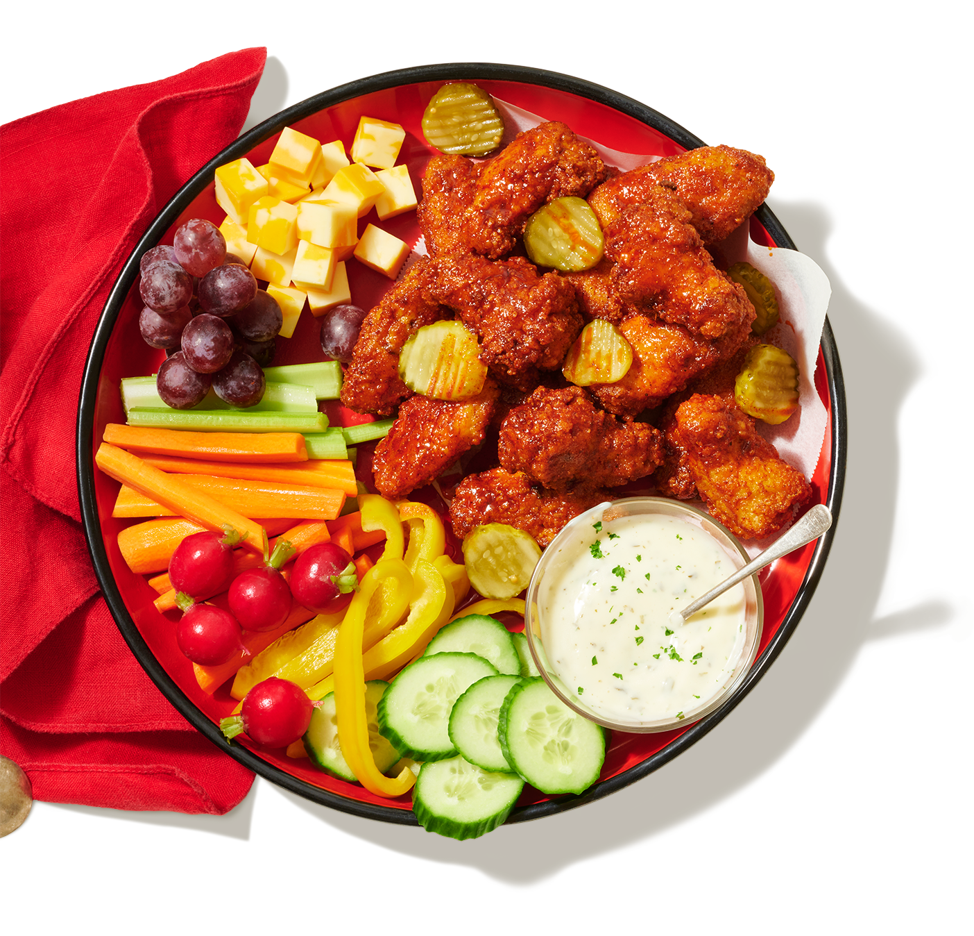 Un grand plateau de service avec une variété de crudités, du fromage, des Ailes de poulet style Nashville PC et un bol de trempette.