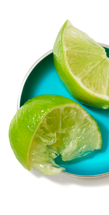 Two small lime wedges on a small dish, one which is fresh, the other previously squeezed.