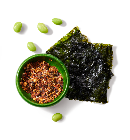 Du nori et des edamames sur une surface à côté d'un petit bol d'assaisonnements.