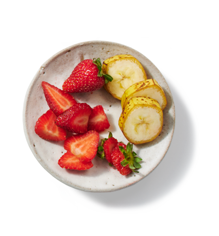 Une petite assiette contenant des portions de fraises et bananes tranchées.