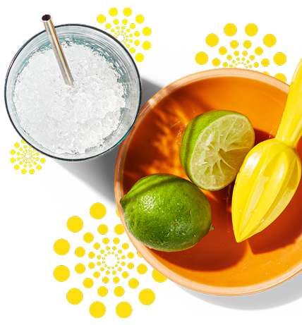 A glass of jalapeno lemonade with a bowl next to it with limes