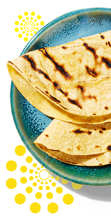Une petite assiette avec deux tortillas de maïs pliées en deux.