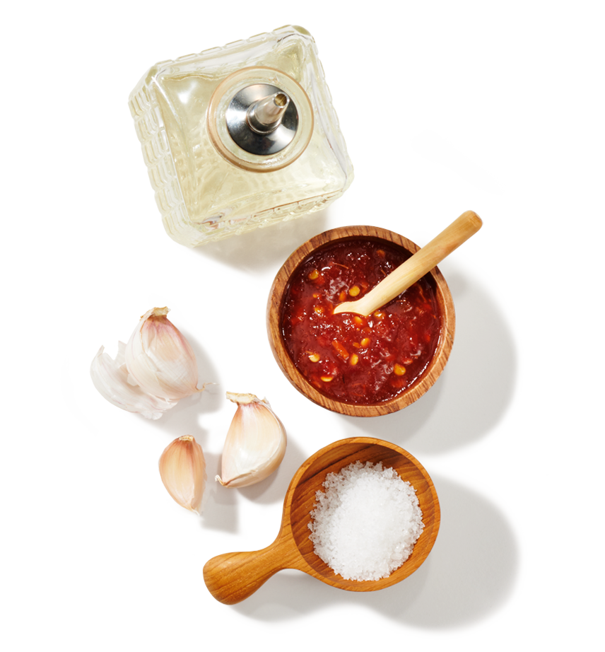 A jar of vinegar, a bowl of chili peppers, a few cloves of garlic and some coarse sea salt