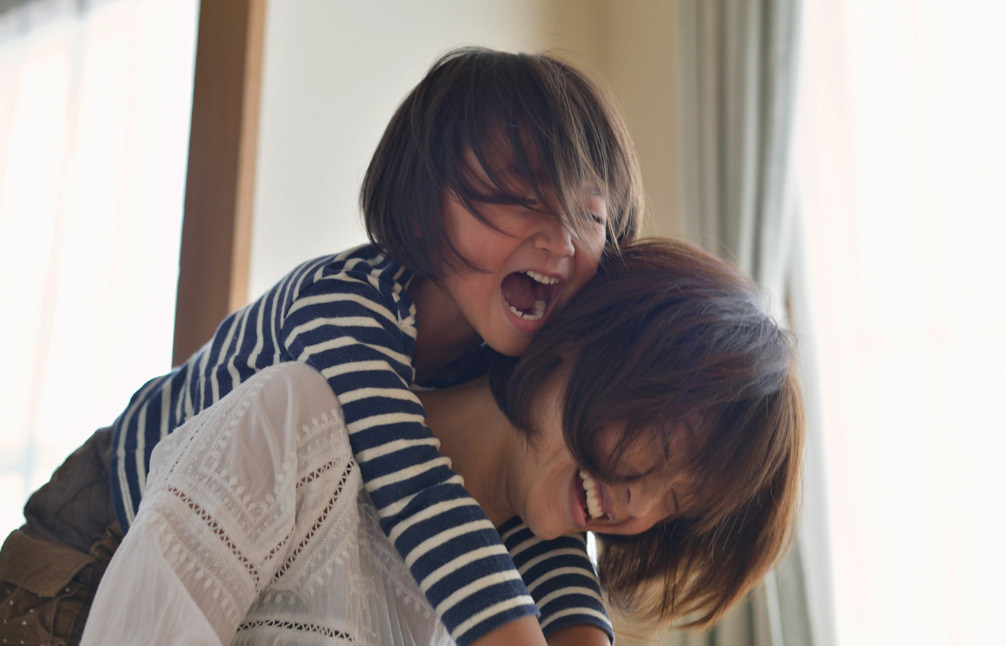 Daughter hanging off mothers back, both our smiling and laughing.