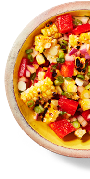 A plate containing a Corn and Tomato Salad with Crispy Corn Flakes on top.