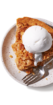 A slice of plant-based apple pie a la mode on a plate ready to be served