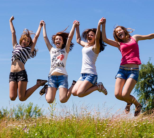 Mavi gökyüzü arka plan atlama dört genç kız grubu