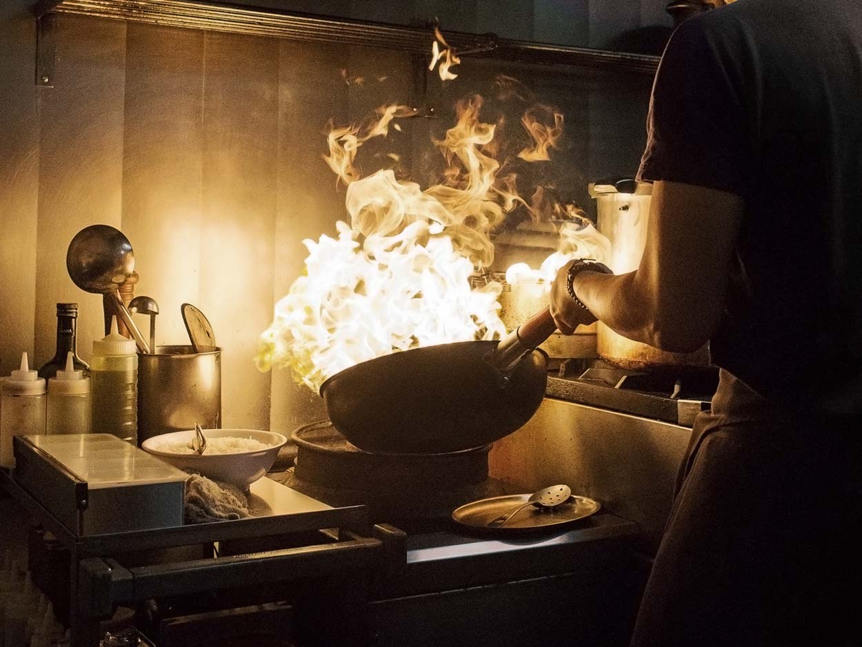 Chef handling a flaming wok pan