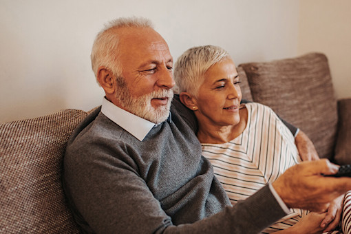 Old couple watching TV on couch