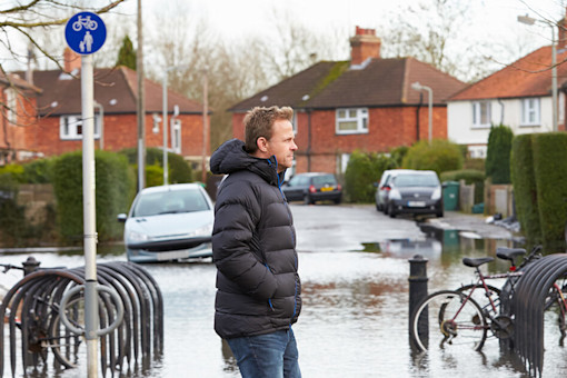Man walking along flooded urban street