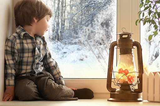 Young boy looking out the window at snow