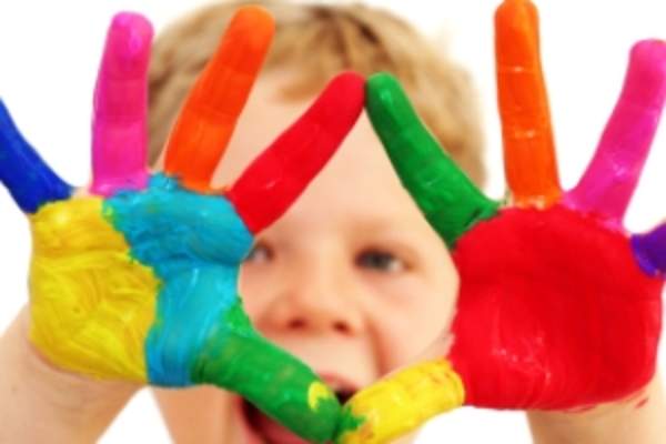 Young boy with hands covered in fingerpaint.
