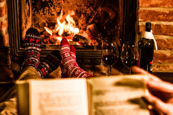 Two people taking relaxation in front of fireplace.