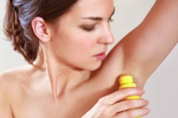 Young woman putting on deodorant image.
